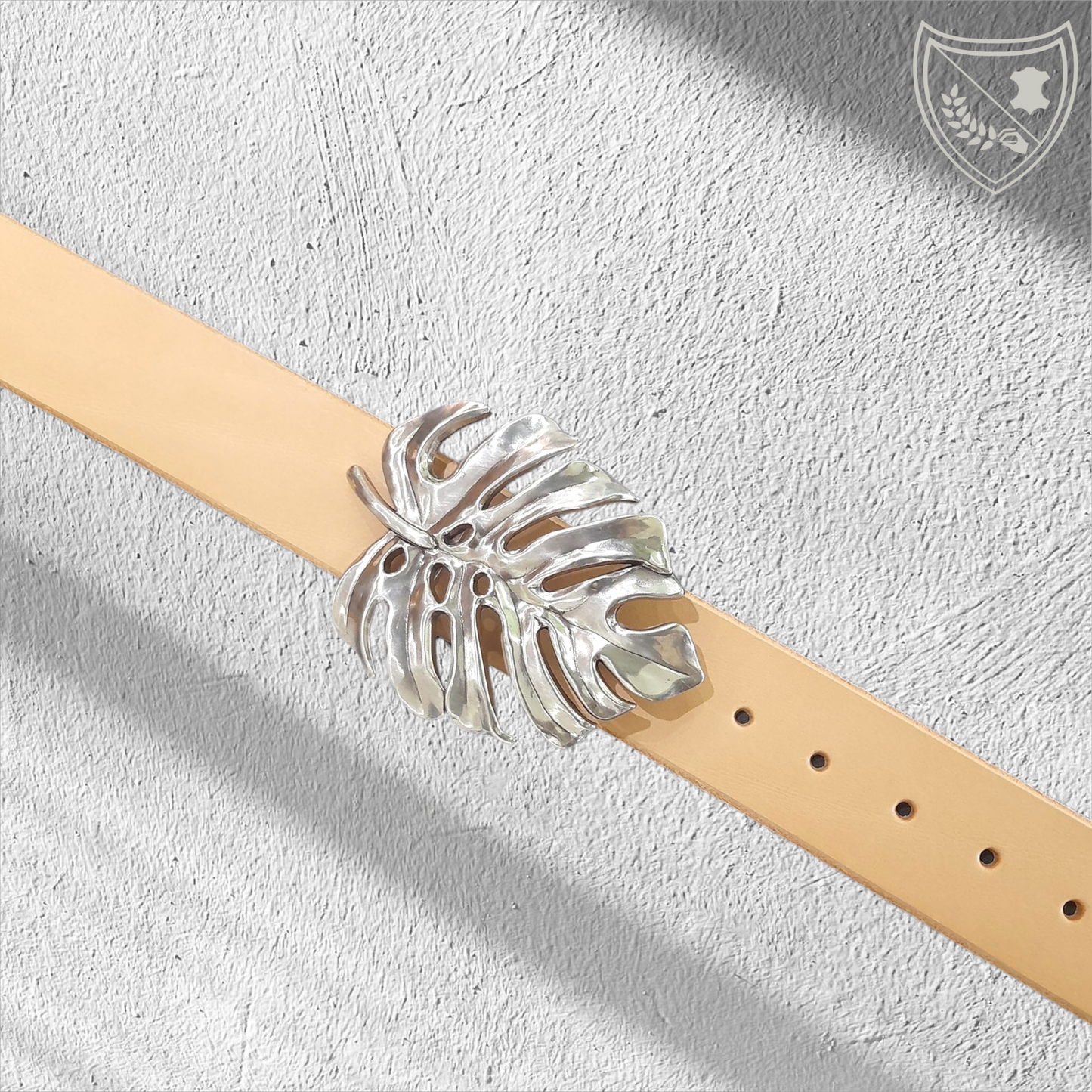 Ceinture cuir végétal de couleur naturelle avec boucle de ceinture Monstera en métal argenté, feuille ajourée au design organique, élégante et affirmée, fermoir fiable pour confort et maintien.
