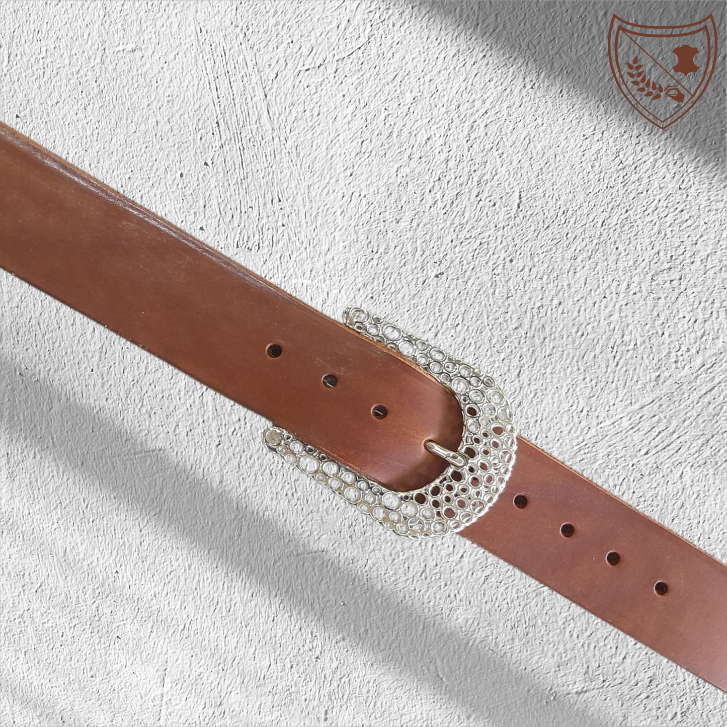 Ceinture cuir tannage végétal couleur havana avec boucle de ceinture Guépard en métal argenté brillant, design perforé qui capte la lumière, allure moderne et intemporelle, fermoir fiable pour confort et maintien du bureau aux soirées. 