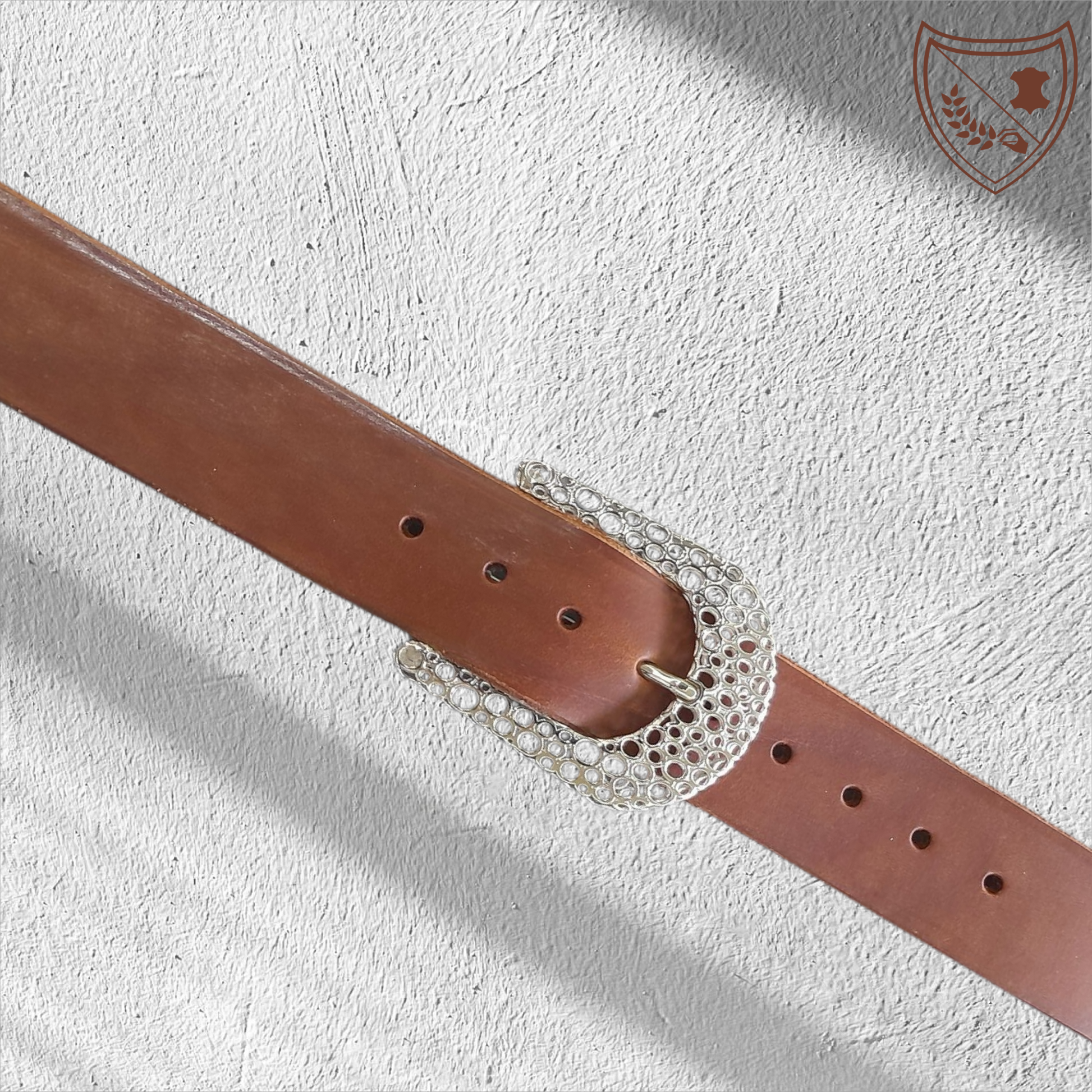 Ceinture cuir tannage végétal couleur havana avec boucle de ceinture Guépard en métal argenté brillant, design perforé qui capte la lumière, allure moderne et intemporelle, fermoir fiable pour confort et maintien du bureau aux soirées. 