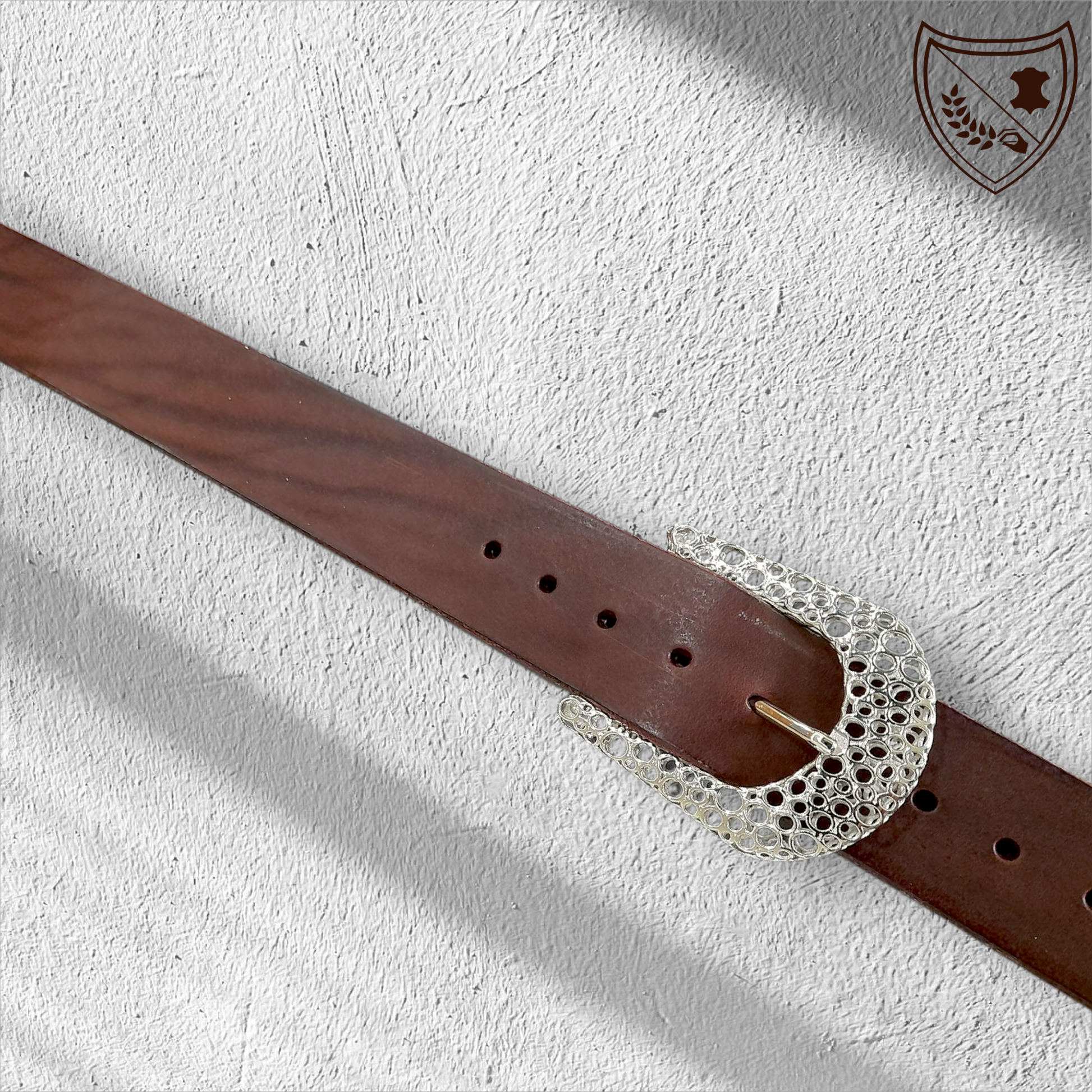 Ceinture cuir tannage végétal couleur chocolat avec boucle de ceinture Guépard en métal argenté brillant, design perforé qui capte la lumière, allure moderne et intemporelle, fermoir fiable pour confort et maintien du bureau aux soirées. 