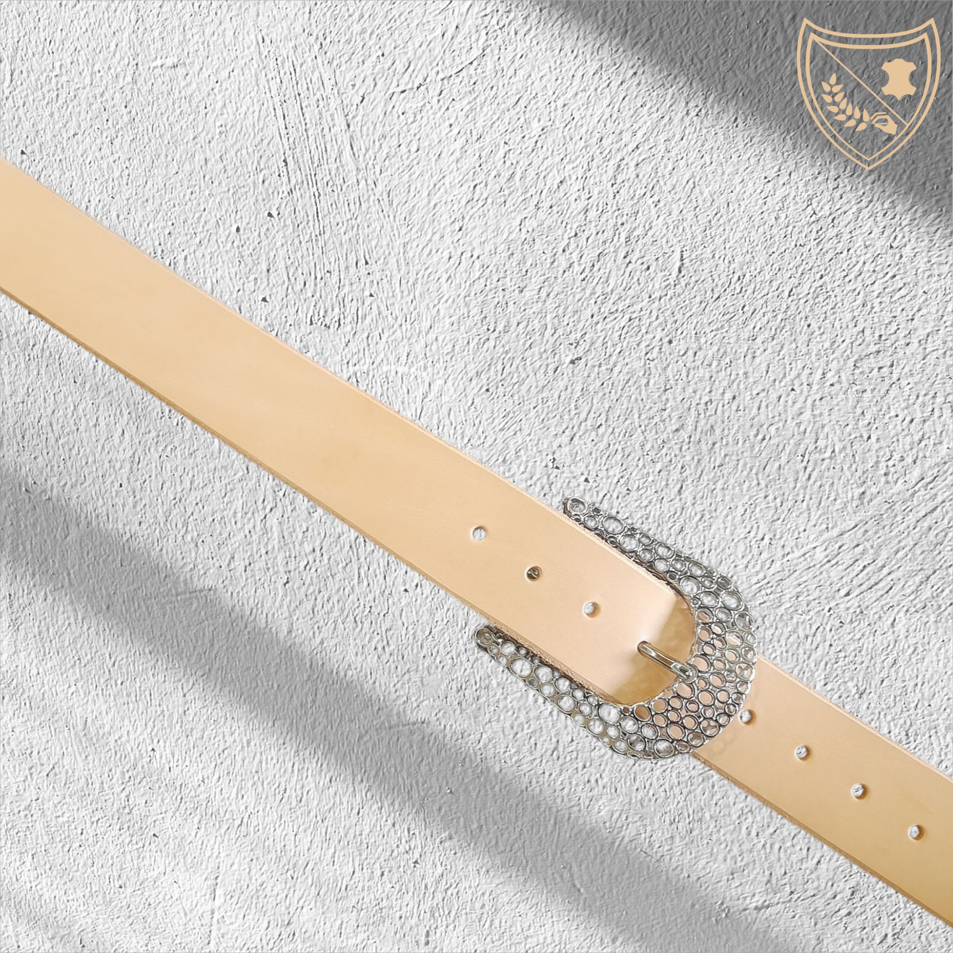 Ceinture cuir tannage végétal couleur naturelle avec boucle de ceinture Guépard en métal argenté brillant, design perforé qui capte la lumière, allure moderne et intemporelle, fermoir fiable pour confort et maintien du bureau aux soirées. 