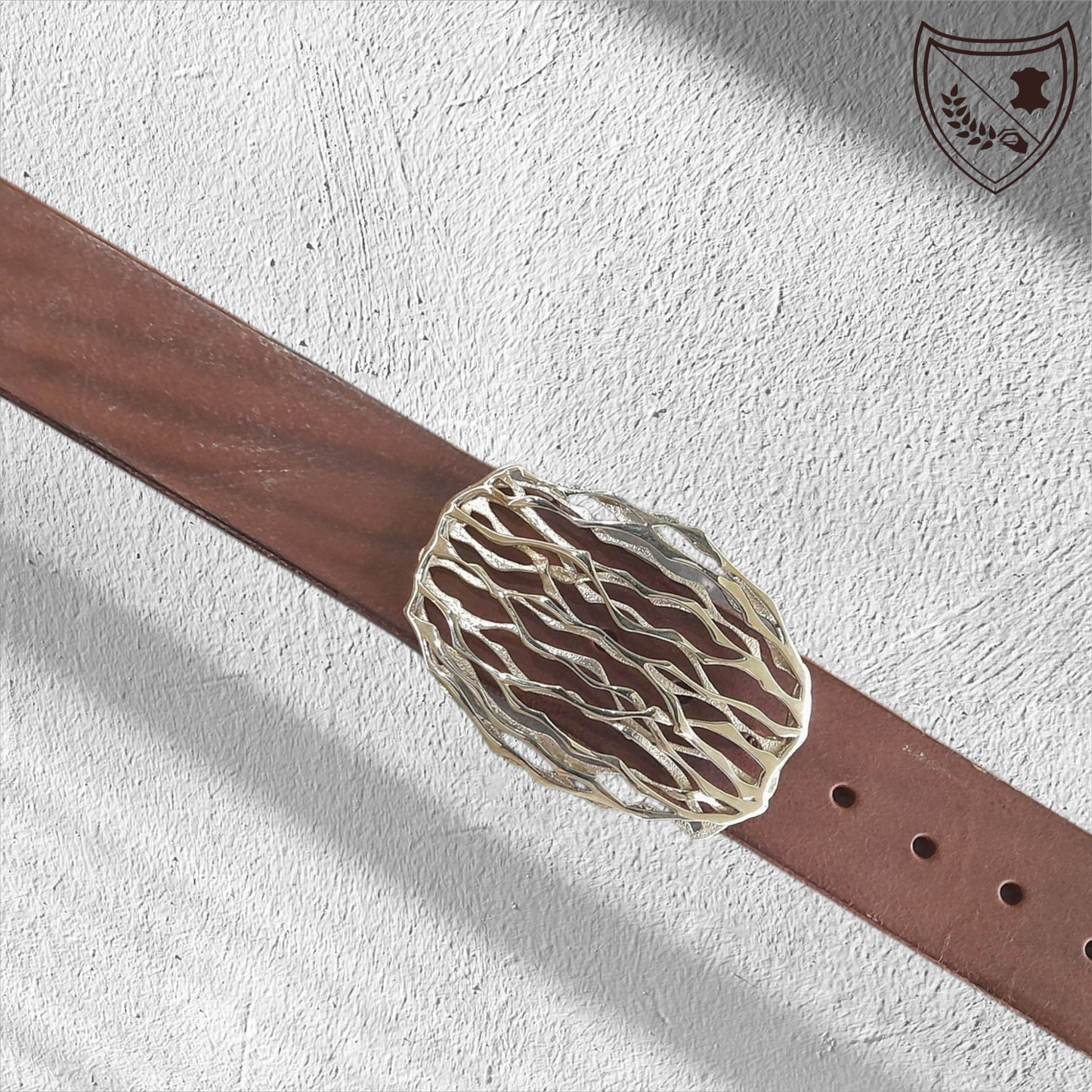 Ceinture cuir tannage végétal couleur chocolat avec boucle de ceinture Wave, lignes ondoyantes organiques inspirées de la nature, allure fluide et singulière, pièce artistique moderne, fermoir fiable pour confort et maintien. Vue de face 