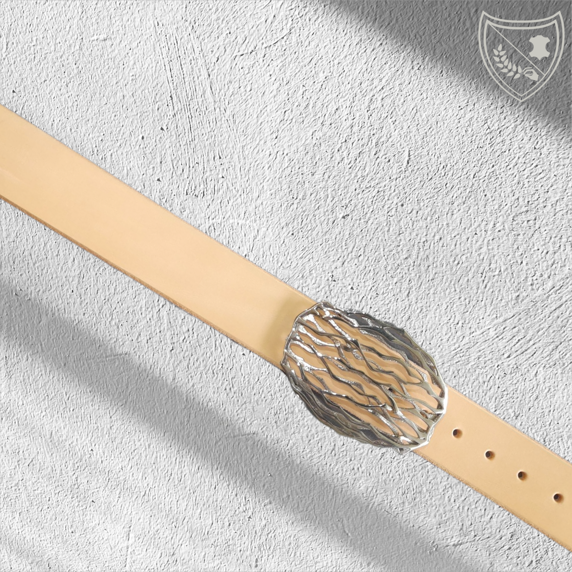 Ceinture cuir tannage végétal couleur naturelle avec boucle de ceinture Wave, lignes ondoyantes organiques inspirées de la nature, allure fluide et singulière, pièce artistique moderne, fermoir fiable pour confort et maintien. Vue de face 