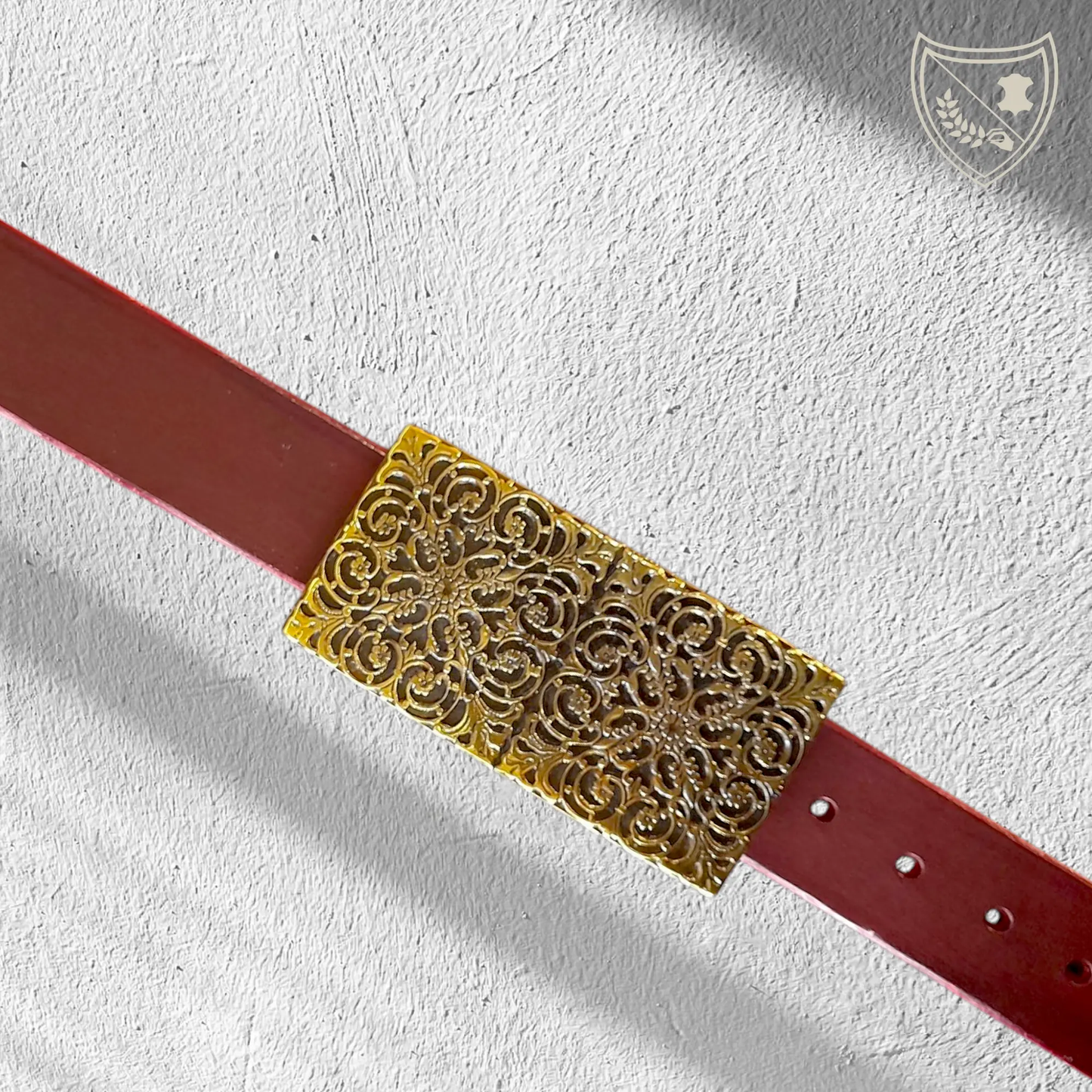 Ceinture cuir tannage végétal couleur victoria avec boucle de ceinture à arabesques florales en relief, profondeur somptueuse aux reflets captivants, charme oriental intemporel, fermoir fiable pour confort et maintien. 