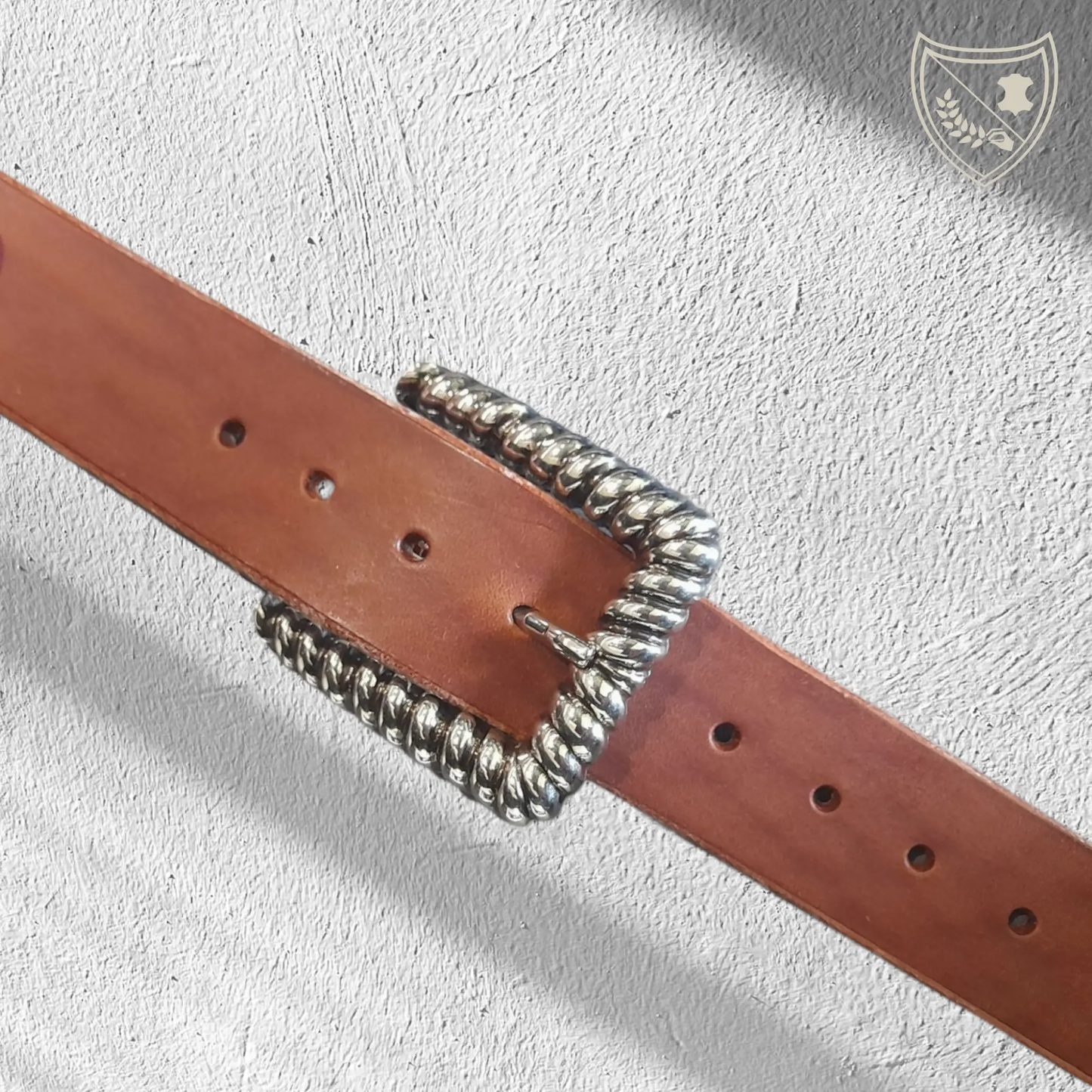 Ceinture cuir tannage végétal couleur havana avec boucle de ceinture Twist en métal argenté, contour torsadé en spirale, jeux de lumière pour allure sculpturale, élégance moderne et intemporelle, fermoir fiable pour confort et maintien.
