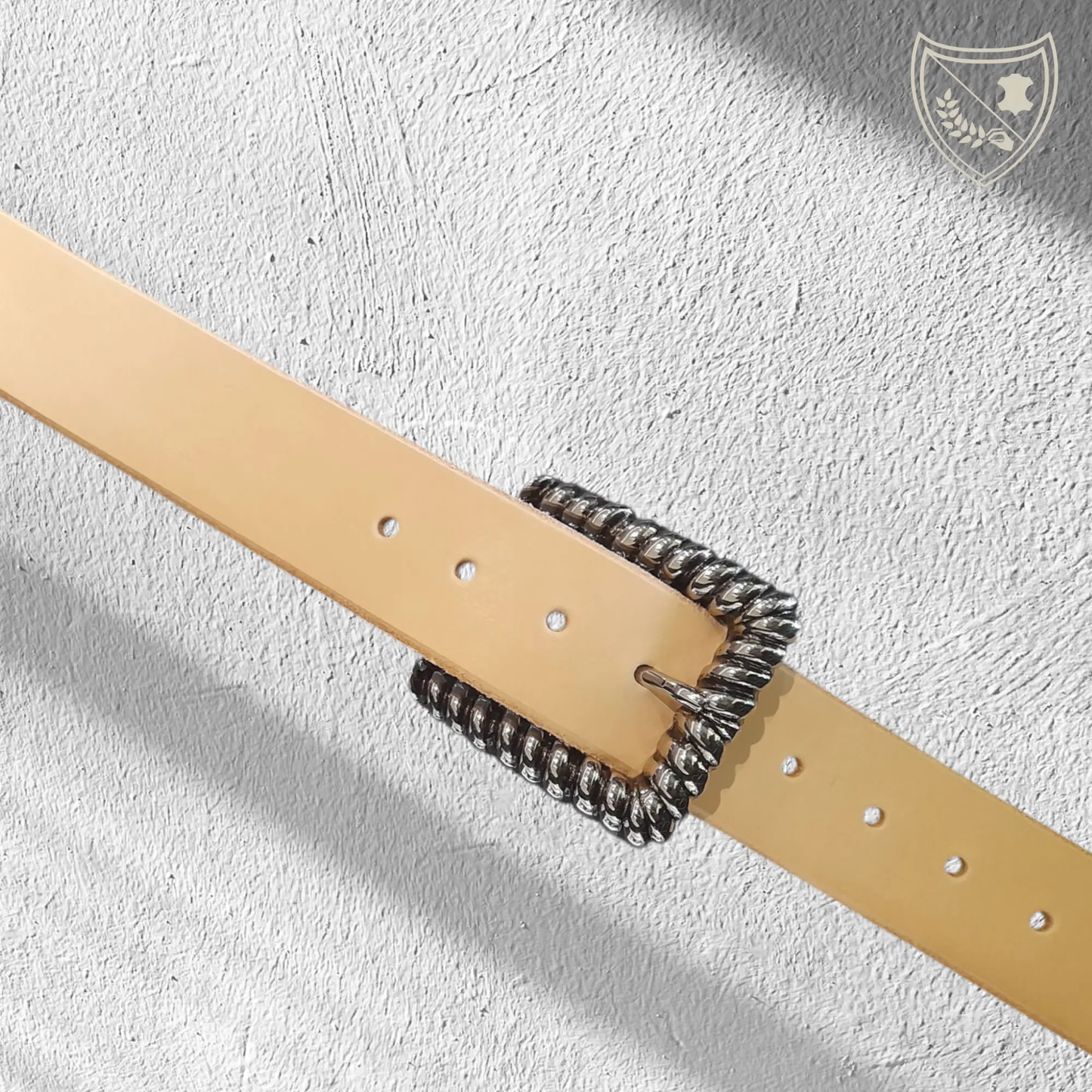 Ceinture cuir tannage végétal couleur naturelle avec boucle de ceinture Twist en métal argenté, contour torsadé en spirale, jeux de lumière pour allure sculpturale, élégance moderne et intemporelle, fermoir fiable pour confort et maintien.